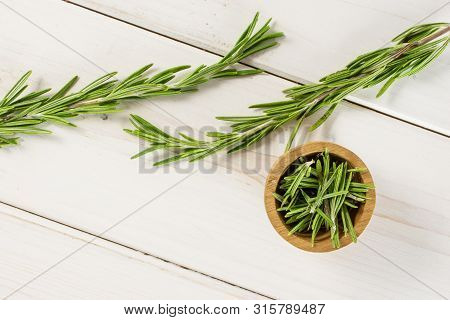 Group Of Two Whole Lot Of Pieces Of Fresh Evergreen Sprig Of Rosemary In A Wooden Bowl Flatlay On Wh