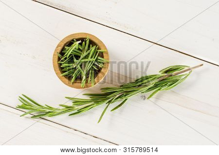 One Whole Lot Of Pieces Of Fresh Evergreen Sprig Of Rosemary In A Wooden Bowl Flatlay On White Wood