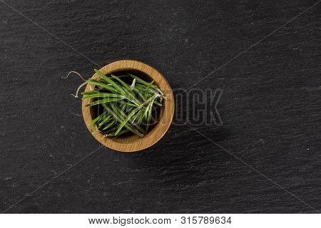 Lot Of Pieces Of Fresh Evergreen Sprig Of Rosemary In A Wooden Bowl Flatlay On Grey Stone