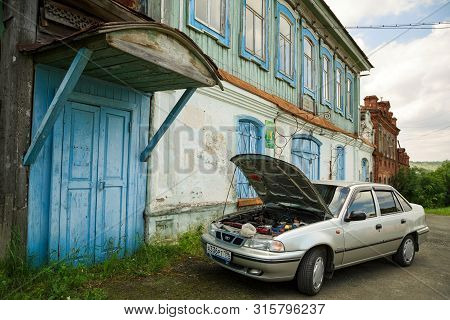 Visim, Russia - June 27, 2015. Modern Car With An Open Hood Parked In Front Of The Historical Buildi
