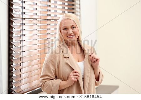 Portrait Of Happy Mature Woman Near Window Indoors