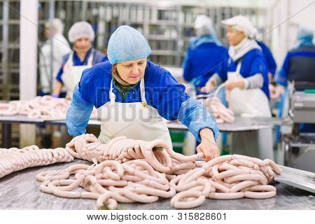 Butchers Processing Sausages At The Meat Factory.