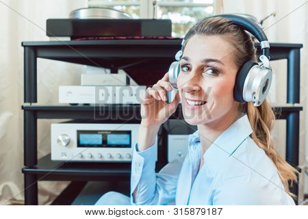 Audiophile woman enjoying music in her home looking at the camera