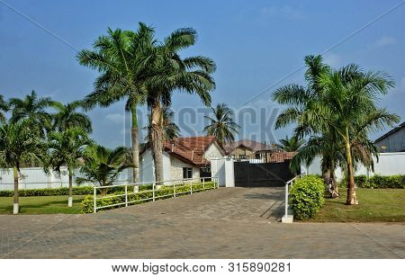Housing In West Africa. Real Estate. Beautiful Urban Landscape With A House And Palm Trees. Resident