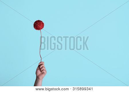 Red Thread Ball, Floating Like A Balloon And A Woman Hand Holding It. Weird Childhood Concept. Minim
