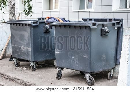 Dumpsters On The Grey Wall Background. Garbage Bins Near Housing