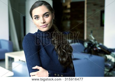 Portrait Shot Of Beautiful Young Woman Wearing Roll Neck Sweater And Smiling While Standing With Arm