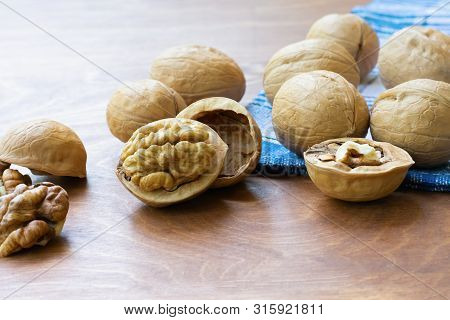 Whole Walnuts And Walnut Kernel Halves Without Shell On A Dark Wooden Table And Checkered Towel, Clo