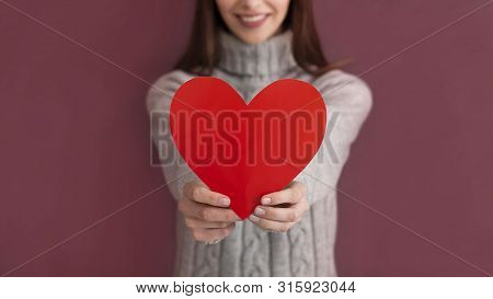 Love Concept. Cropped View Of Smiling Girl In Sweater, Holding Heart Shaped Card Isolated