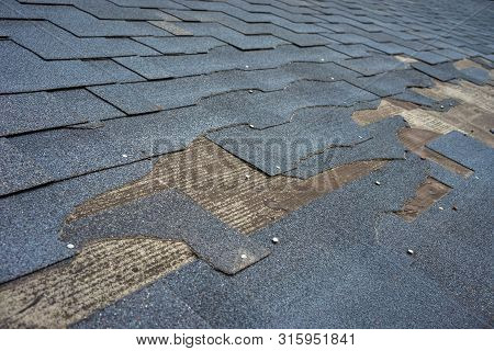 Сlose Up View Of Bitumen Shingles Roof Damage That Needs Repair.