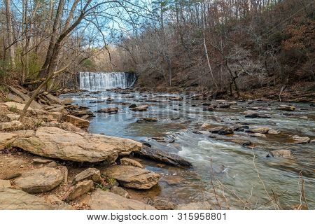 Open View Of The Waterfall In Winter On A Sunny Day With Rocks And Boulders In The Foreground