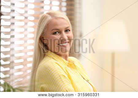 Portrait Of Happy Mature Woman Near Window Indoors