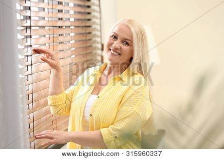 Portrait Of Happy Mature Woman Near Window Indoors