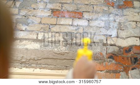 Priming Walls. Worker Primers The Wall With A Spray Gun. Pulverizer Soiled In Paint. Green Spray Gun