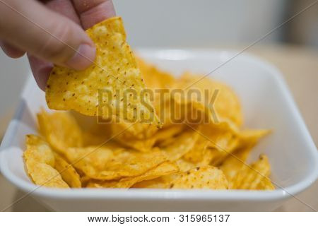 Man Hand Picking Up Corn Chip From White Bowl