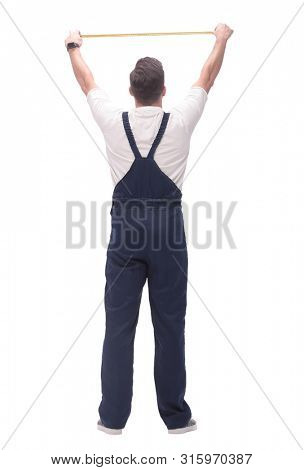 rear view. a man measuring something with a construction tape measure.