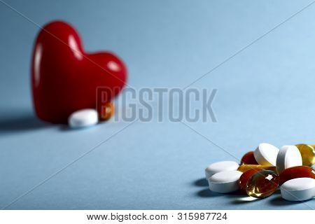 A Lot Of Bright Colored Medicine Pills And A Red Heart Figure On A Blue Background. Cropped Shot, Ho