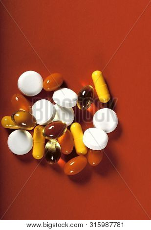 A Lot Of Bright Pills Of Drugs On A Red Background. Cropped Shot, Vertical, Top View, Close-up. The 
