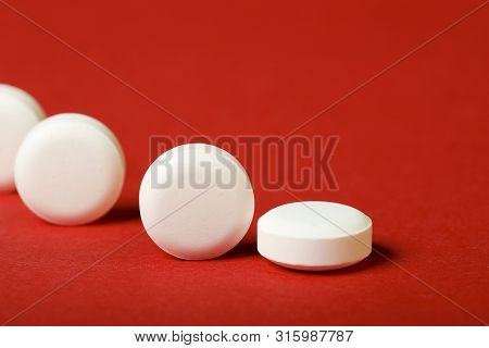 A Row Of Round White Pills On A Red Background. Horizontal, Close-up, Free Space, Without People, Si