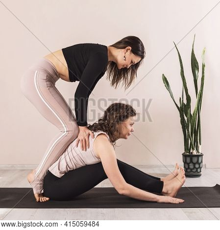 A Female Teacher Of Universal Yoga, Performs Traction Traction Of The Spine To A Student Sitting On 