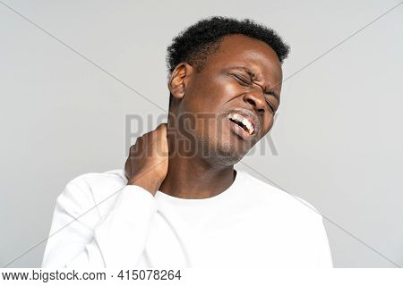 Unhappy Black Man Suffering From Neck Pain, Pinched Nerve In Her Back. African Male Has Spinal Probl
