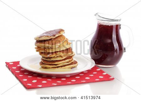 หวาน pancakes บนแผ่นกับนมข้นที่แยกต่างหากบนพื้นสีขาว
