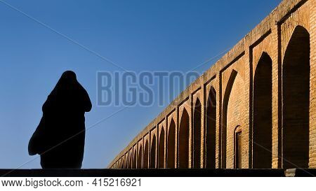 Silhouette Of A Persian Woman In National Dress On The Old Khaju (pol-e Khaju) Bridge In Isfahan. Ir