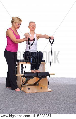 Fifty-year-old Trainer Teaches Pilates Exercises To Elevator Chair, Young Girl With Help Of Gymnasti