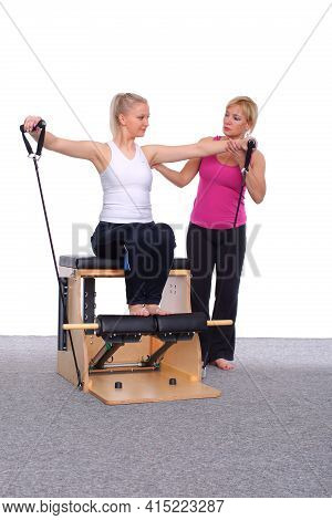 Fifty-year-old Trainer Teaches Pilates Exercises To Elevator Chair, Young Girl With Help Of Gymnasti