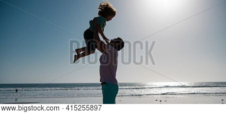 Father Throws Son Up Against The Blue Sky. Handsome Man Father Carrying Young Boy Son. Happy Dad Hol