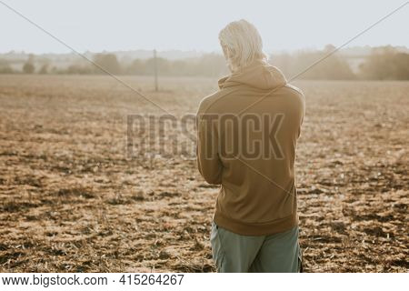 Man in stretchy hoodie in the countryside at sunset