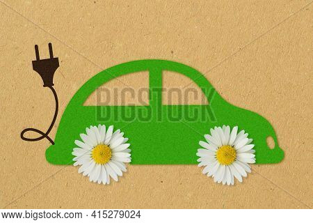 Green Paper Car With Daisy Flowers And Electric Plug On Recycled Paper Background - Concept Of Elect