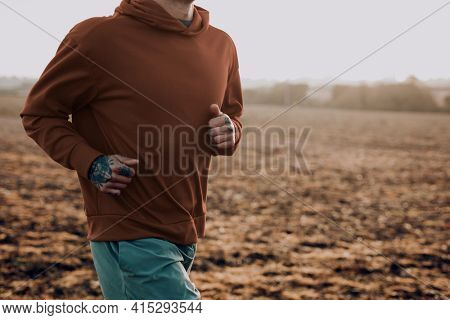 Man in stretchy hoodie in the countryside at sunset