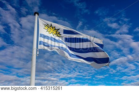Uruguay Flag, Oriental Republic Of Uruguay National Symbol On A Flagpole Waving Against Blue Cloudy 