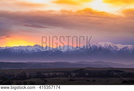 Dramatic Early Sunrise Landscape Over Carpathian Mountains Covered In Snow With Beautiful Orange Sky
