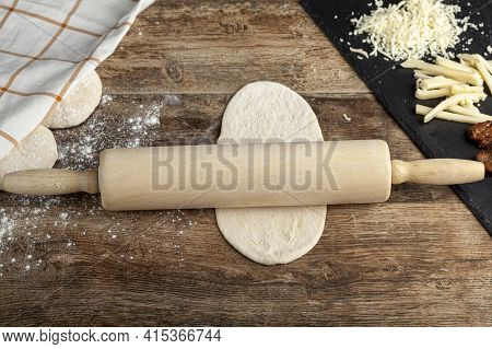 Closeup Image A Baker's Wooden Rolling Pin On  A Flattened Dough On Wood Kitchen Countertop. A Bread