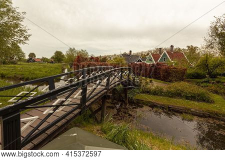 Landscape Image Of A Small Village Near Hague, Netherlands With A Tiny Creek, Grassland, Shrubs, Tre