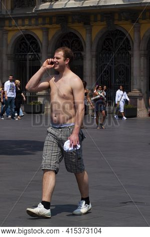 Barcelona, Spain 05/01/2010: A Shirtless Man Wearing A Short And Sneakers Is Talking On The Phone Wh