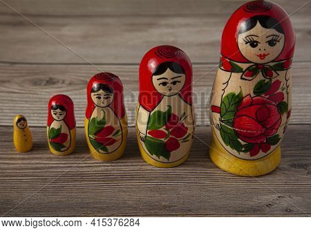 A Line Up Of Handmade Russian Matrushka Dolls On Wooden Background. These Folkloric Women Figurines 