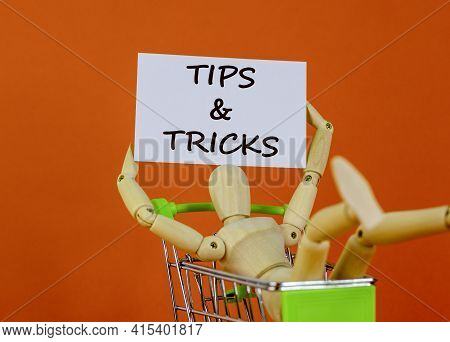 Tips And Tricks Symbol. White Paper. Words 'tips And Tricks'. Miniature Shopcart, Wooden Human. Beau