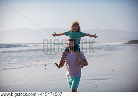 Father Giving Son Ride On Back Outside. Little Boy Kid With Daddy Carrying Him On Shoulders. Dad And