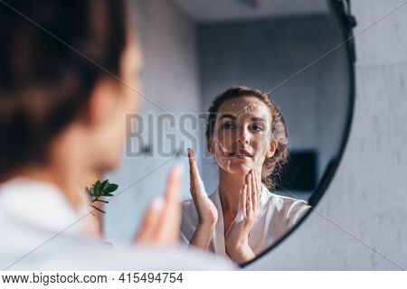 Woman Washes In Front Of The Mirror, Applying Foam To Her Face