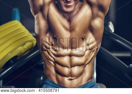 Fit Man Training Training Abs Muscles At Gym. Pumping Up Abdominal Exercise. Close Up Muscles At Wor