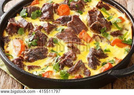 Delicious Baked Beef With Vegetables In Egg Sour Cream Sauce Close-up In A Frying Pan On The Table. 