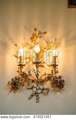 Gold Three-lamp Floor Lamps, Decorated With Floral Patterns On The Wall. Interior Details Of An Old 