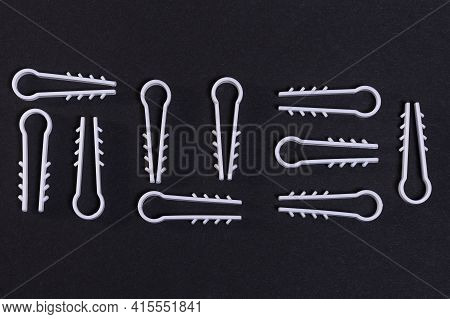 White Plastic Clips For Attaching The Electrical Cable To The Wall. Technological Cuneiform Pattern 