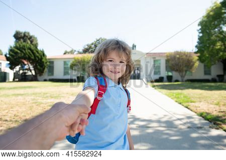 Little Boy Holding Parent Fathers Hand With Backpack On Blurred School Building Background