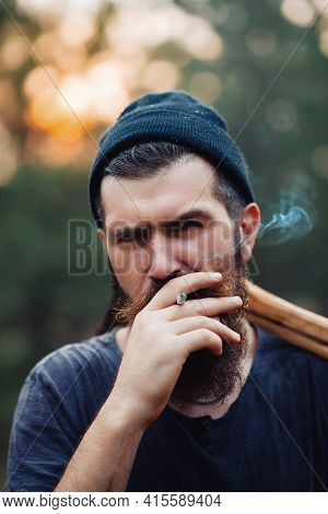Bearded Stylish Man In A Dark Sleeveless T-shirt And In A Warm Hat With A Large Mustache And Gray Ha