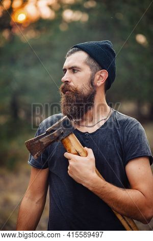 Stylish Brutal Bearded Man Lumberjack With A Long Beard And Mustache In A T-shirt And A Warm Hat Wit