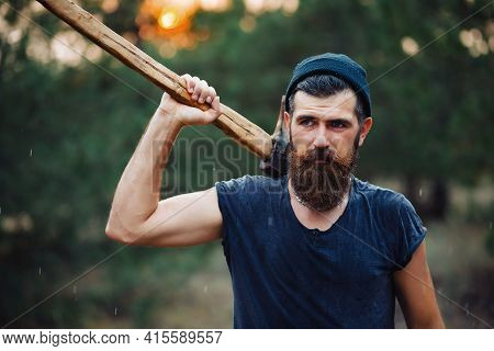 Lumberjack Man With A Thick Beard And A Large Mustache In A Dark Sleeveless T-shirt And A Warm Hat W